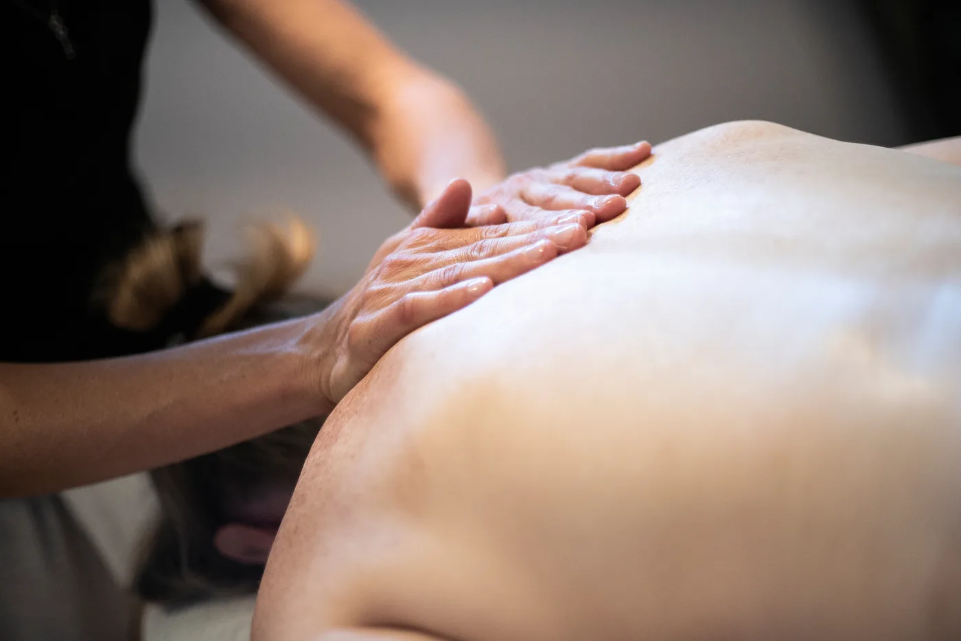 Les deux mains d'Isabelle glissent l'une derrière l'autre le long du dos d'une personne couchée sur le ventre